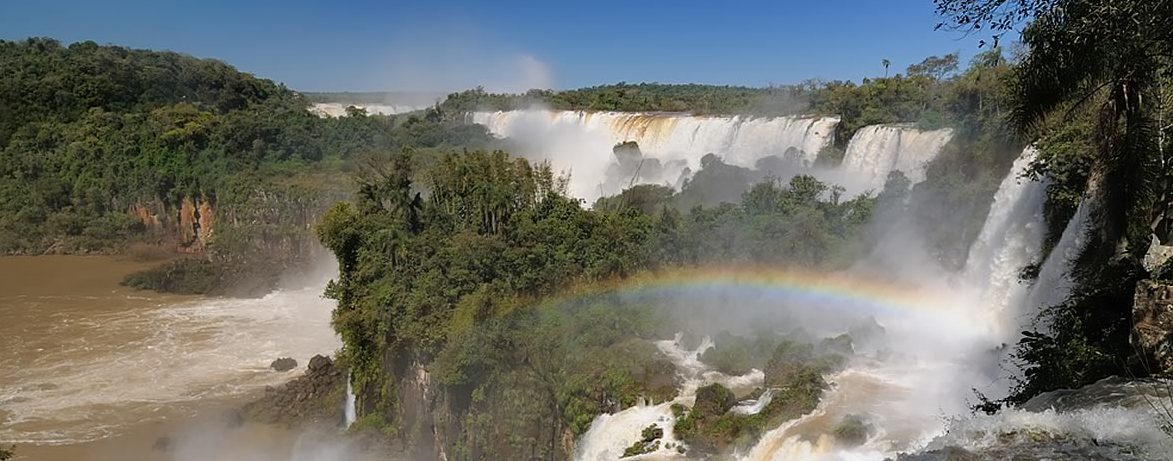 A rainbow forms over the Iguazu falls. 