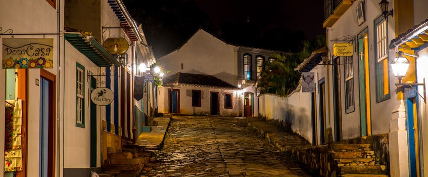 Minas Gerais, a cobbled street lit by street lamps in the evening. 