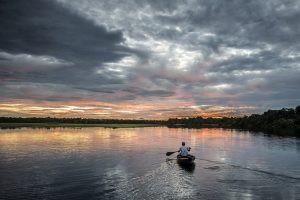 A lone rower, rows his boat into the sunset. 