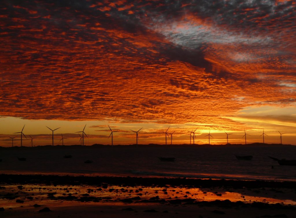 The sunset sets the sky in fire with a windfarm in the background. 