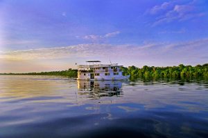 The light of the sunset reflects off the Amazon river and shines on an Amazon Cruise boat. 