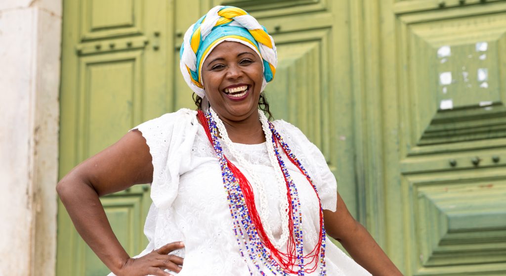 A smiling lady on her porch in traditional Bahian dress. 