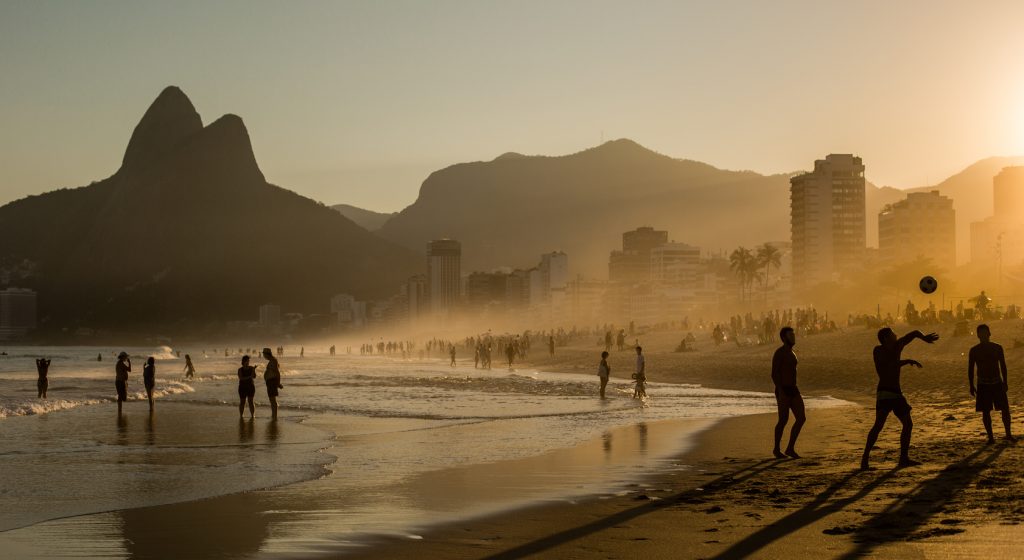 Sunset at Copacabana beach, silhouettes playing football on the sand. 
