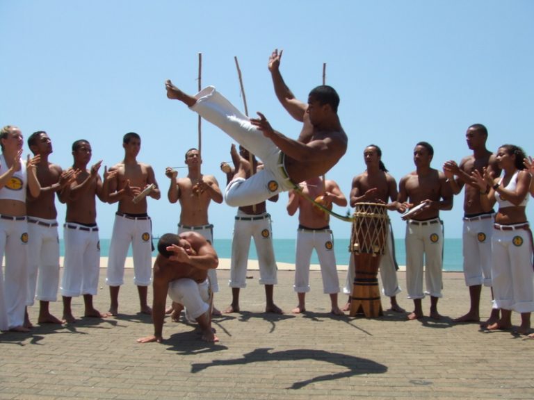 A band practicing capoeira by the beach